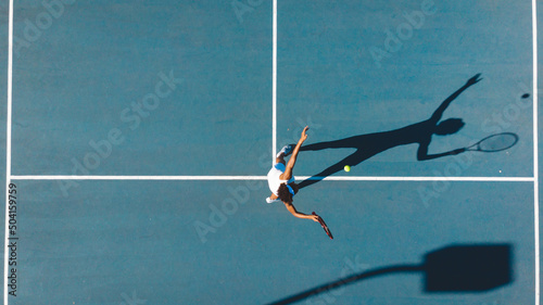 Overhead view of african american young female player serving on blue tennis court during sunny day