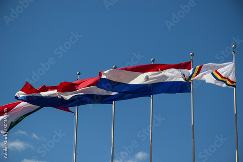 Paraguay - Itapua - Encarnacion - Waving flags of Paraguay country, Itapua department and Encarnacion city at the flagstaffs on plaza de Armas in Encarnacion