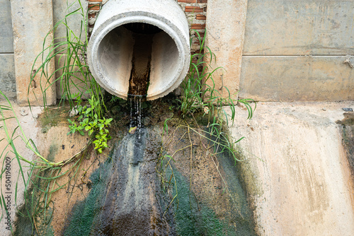 Industrial sewage water draining out from cement tube into the environmental. Industrial pollution scene photo.