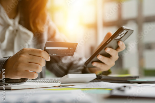 Beautiful woman holding a credit card, she uses a credit card to pay for goods and services online, the concept of using a credit card for online shopping, ordering goods and services on the website.