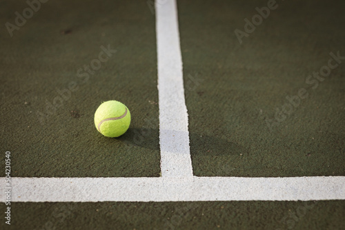 High angle view of yellow tennis ball by white lines on tennis court, copy space