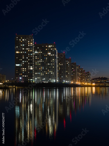 Night city. Houses are reflected in the water. Siberian city of Krasnoyarsk
