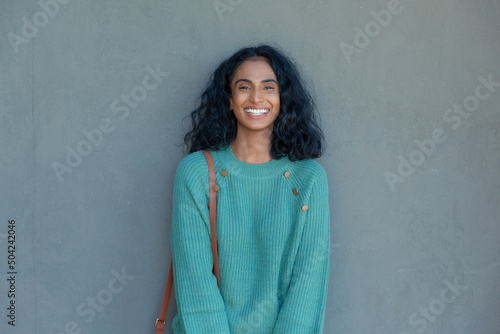 Portrait of happy young biracial businesswoman standing against gray wall with copy space