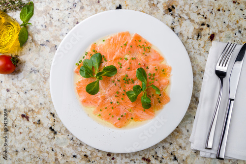 Salmon carpaccio on a white plate on marble table top view