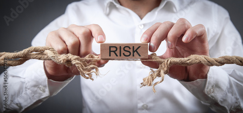 Man with a frayed rope showing Risk word on wooden block. Risk
