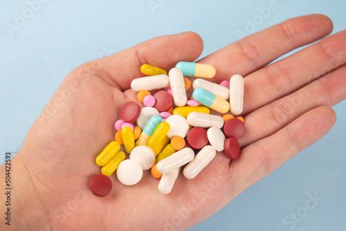 Man holding variety of medicine pills, capsules and tablets in his hands. A handful of pills. Immune system vitamins and supplemets. Man's health concept. Selective focus