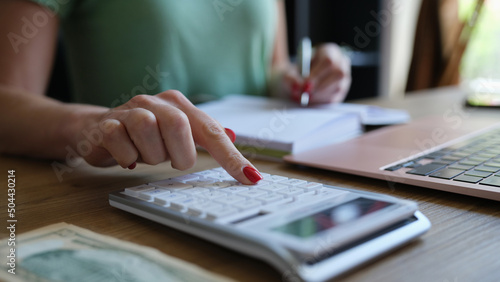 Hands of young woman typing on keyboard of computer and digital calculator preparing electronic payments for bills