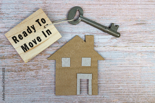 Ready to move in text on wooden keychain with house model and key on wooden desk