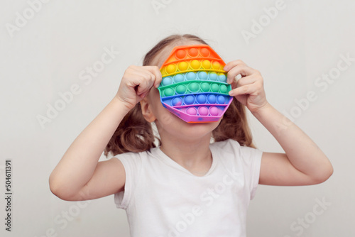 A girl plays with a popular toy multi-colored pop it in the form of an octahedron