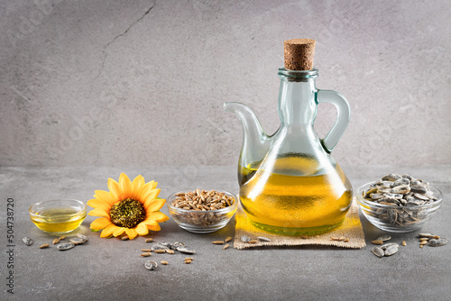 Sunflower oil and sunflower seeds on dark concrete background with copyspace.