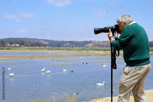 man with his camera enjoying his hobby of birdwatching in a wetl