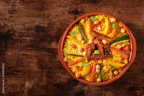 Moroccan couscous with meat, traditional festive dinner, shot from above on a wooden background with copy space