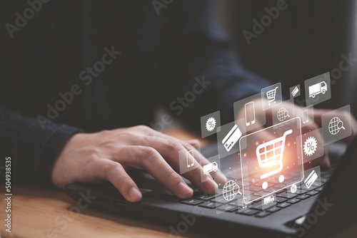 Shopper using computer laptop to input order with trolley credit card delivery truck for online shopping and e-commerce technology concept.