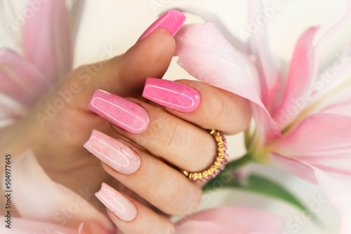 Pink elongated nail extension with fine glitter.