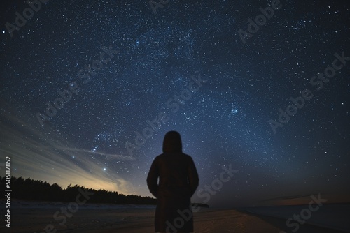 Man stargazing and exploring Milky Way Galaxies. Long exposure photo of a night sky full of stars with the silhouette of a human with no face. Concept of young people dreaming about a bright future.