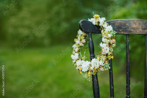 wianek na głowe z delikatnych kwiatuszków wisi na oparciu starego krzesła w ogrodzie