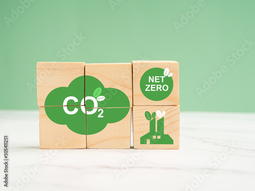Net-zero emissions in 2050. World Earth day concept. Wooden cubes with eco-friendly icons over a marble floor against a green background