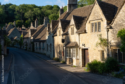 Brown stone cottages surrounded by green vegetation. Castle Combe, England, UK.