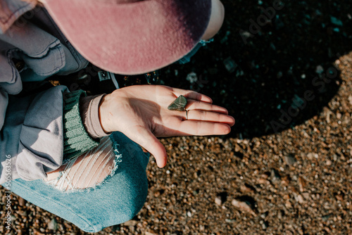Top shot of a female holding a small black rock from the ground in Hopewell rock park on a sunny day