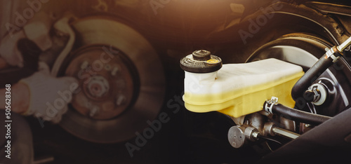 Brake fluid reservoir of car brake system with a disc brake repairing double exposure blurred on background