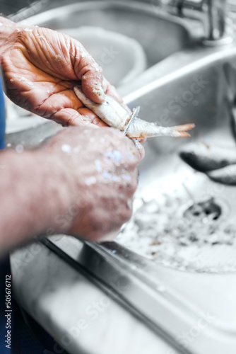 Man hands holding are cleaning fresh fish in kitchen sink with knife, cooking fish dishes