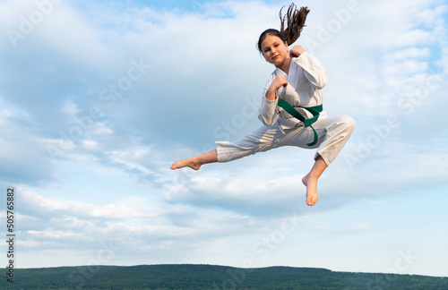 karate girl in kimono jump on sky background