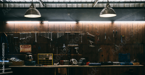 Workshop scene. Old tools hanging on wall in workshop, Tool shelf against a table and wall, vintage garage style