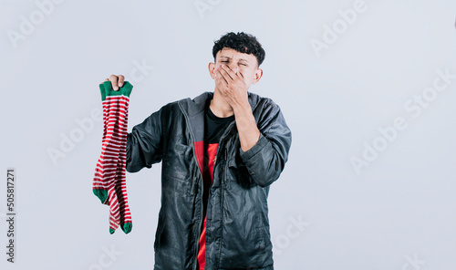Person holding a stinky sock in his hand, A man with a sock in his hand covering his nose, smelly socks concept