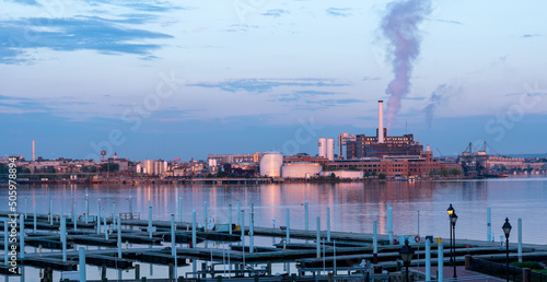 Sunrise over waterfront industrial center with smoke blowing from factory smokestacks in Baltimore Maryland on Potomac Harbor waterfront