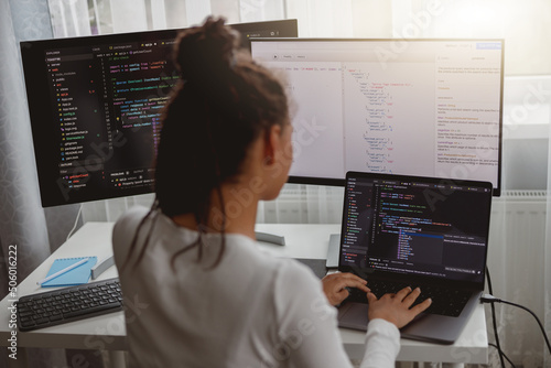 Back view of woman coding on computer, professional female programmer working in room