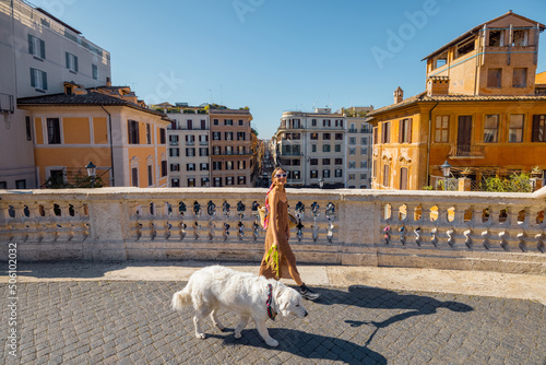 Woman walks with her dog with a beautiful cityscape of Rome on the background on a summer day. Concept of italian lifestyle and travel