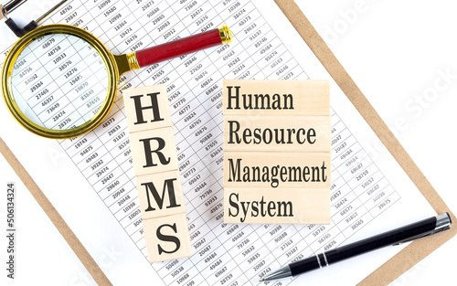 HRMS Human Resource Management System text on wooden block on chart background