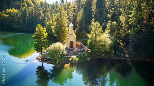 Aerial view of Orthodox Chapel of the Holy Prophet Solomon on the shore of a Emerald Lake among the mountains and forests. Popular tourist destination.