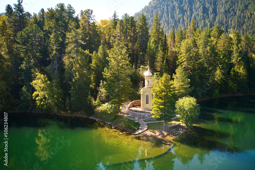 Aerial view of Orthodox Chapel of the Holy Prophet Solomon on the shore of a Emerald Lake among the mountains and forests. Popular tourist destination.