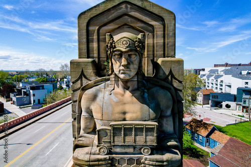 Front view of one of Cleveland's own Guardians of Traffic Statues on a beautiful sunny day. This statue holds a truck and is beautifully colorful from the aging on the sandstone