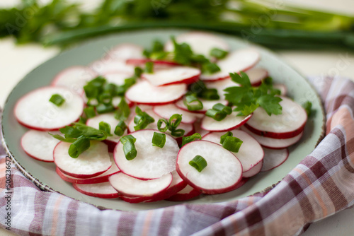 Radish salad in green bowl on wooden table