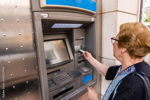 Elderly woman using an ATM in the street