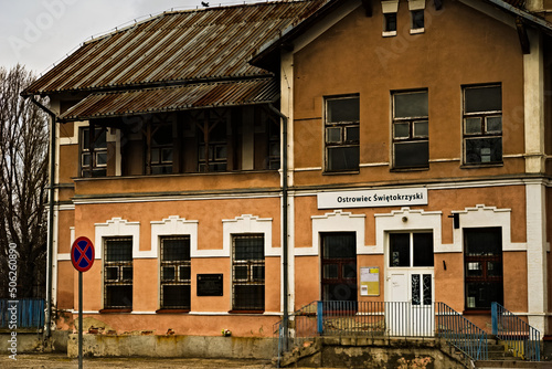 Stary , zabytkowy budynek dworca kolejowego w Ostrowcu Świętokrzyskim . Stacja kolejowa z dachem krytym blachą falistą , pamiątkową tablicą i szyldem z nazwą miasta . Znak zakazu postoju .