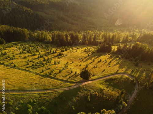 Aerial view of beautiful mountain Carpathians, Ukraine in sunlight. Drone filmed an landscape with coniferous and beech forests, around a winding serpentine road, copter aerial photo