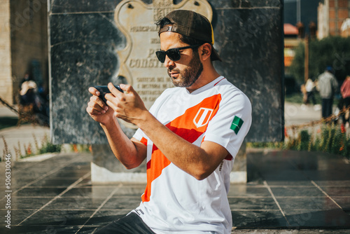 Hincha de futbol peruano sosteniendo su teléfono. Concepto de personas y tecnología.