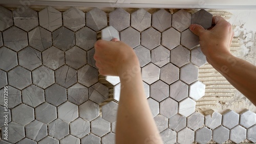 Laying mosaic tiles by the hands of a master. Mosaic tile gluing. The master glues mosaic ceramic tiles on the wall.