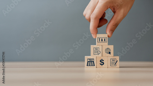 Hand putting tax icon in the wooden cube for income tax return and submit tax for payment tax documents online to the government