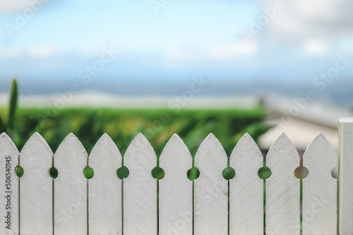 Close up image of white picket fence with beautiful beach scenery out of focus in background providing copy space