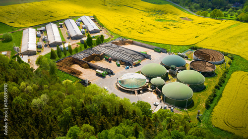 Biogas plant and farm in blooming rapeseed fields. Renewable energy from biomass. Aerial view to modern agriculture in Czech Republic and European Union. 