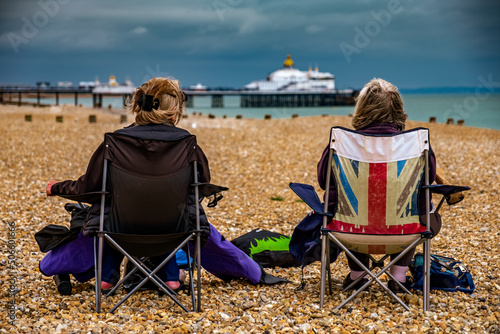 pair of anon persons sitting on beach with union jack chair