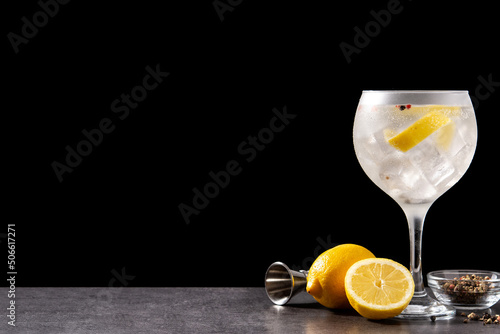 Gin tonic cocktail drink into a glass on black background. Copy space