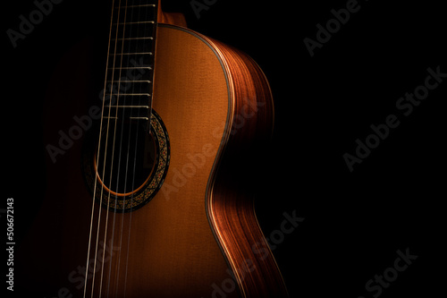 Classical guitar close up, dramatically lit on a black background with copy space.