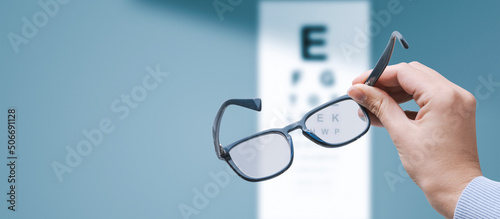 Optometrist holding glasses and eye chart