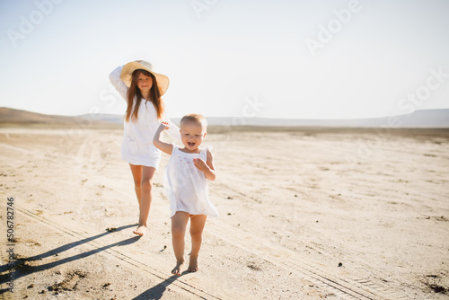 two little sisters walk barefoot in summer run around deserted place in nature, children games and relaxation in the hot summer