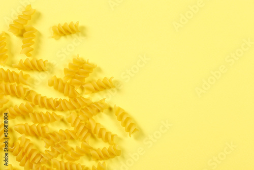 Pasta fusilli on yellow background, flat lay, top view with copy space 